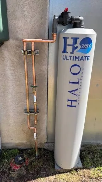 Compact outdoor whole-home water treatment tank installed beside a residence